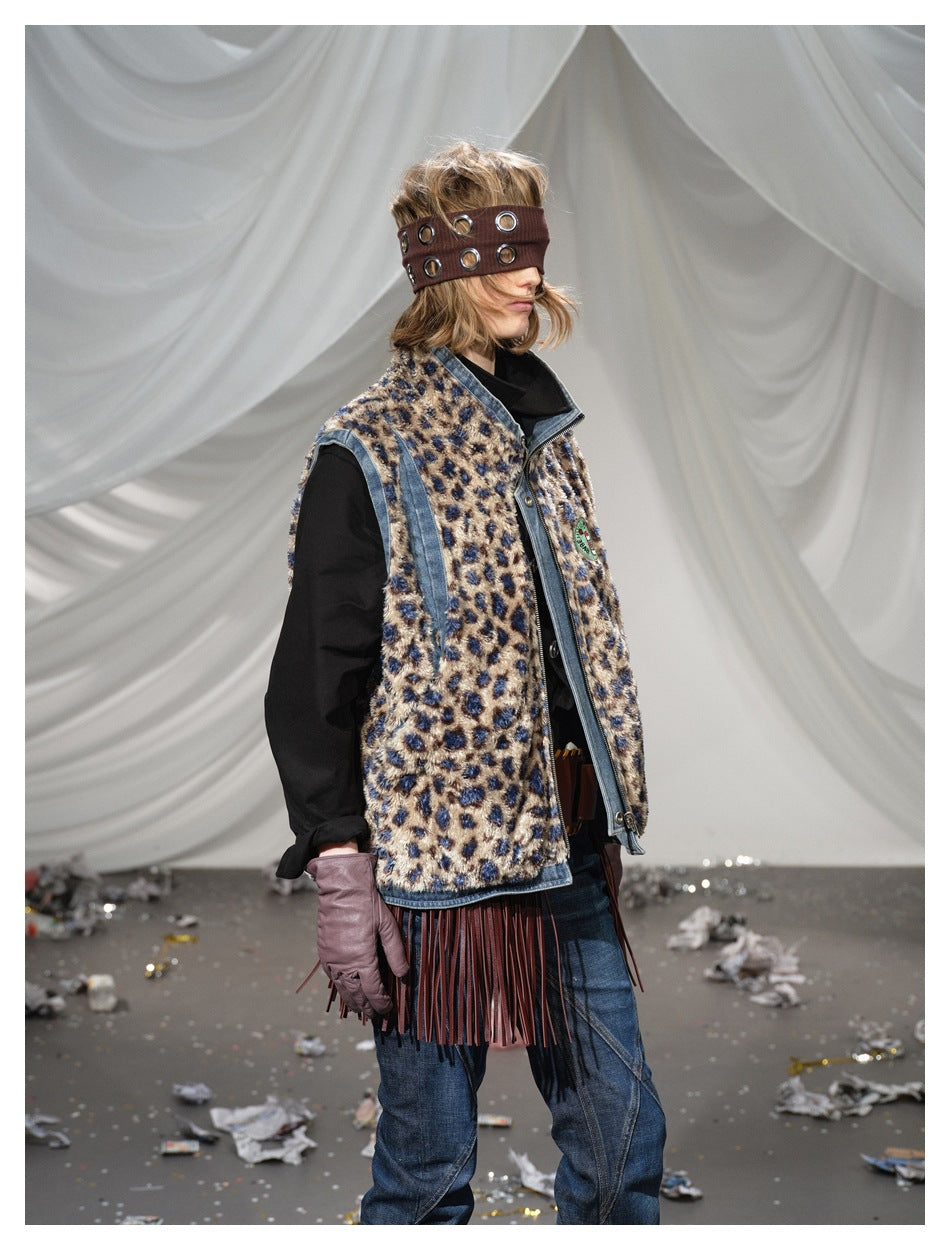 Three-quarter side view of a model wearing a leopard-print vest with denim trim and burgundy fringe over black sleeves.