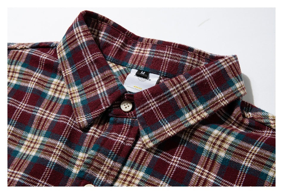 Close-up of a burgundy, teal, and cream plaid shirt collar, placket, and neck label.