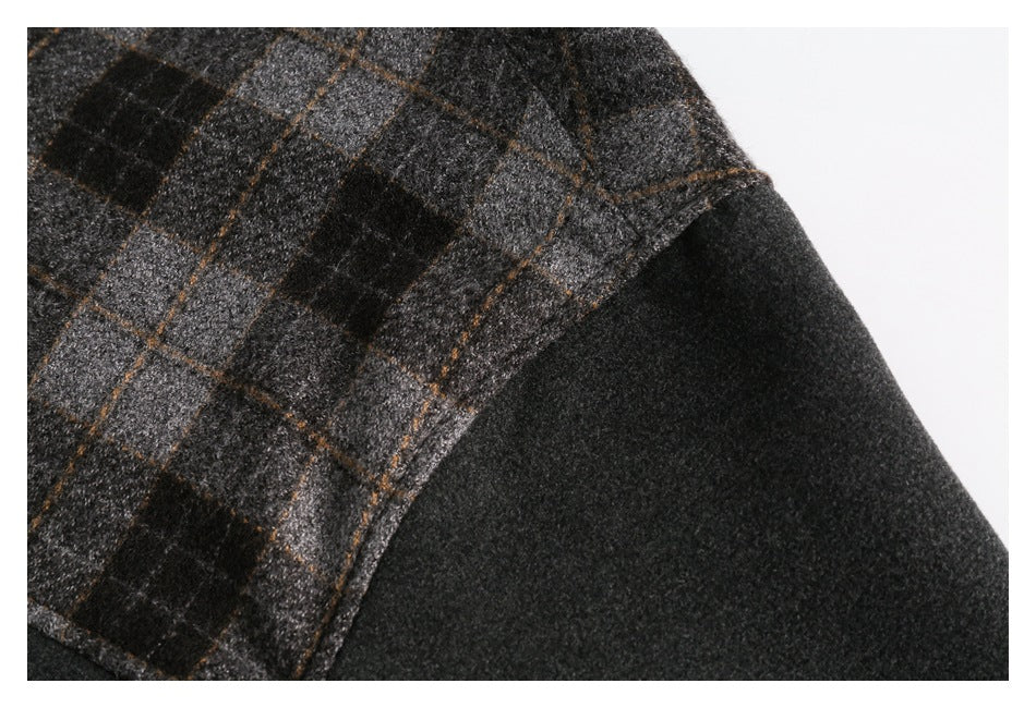 Close-up of a charcoal coat showing a gray plaid panel with thin brown lines beside a solid dark section.