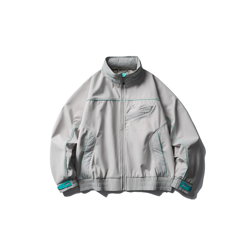 Gray stand-collar zip jacket with teal piping, side panels and teal cuff tabs, flat lay front view