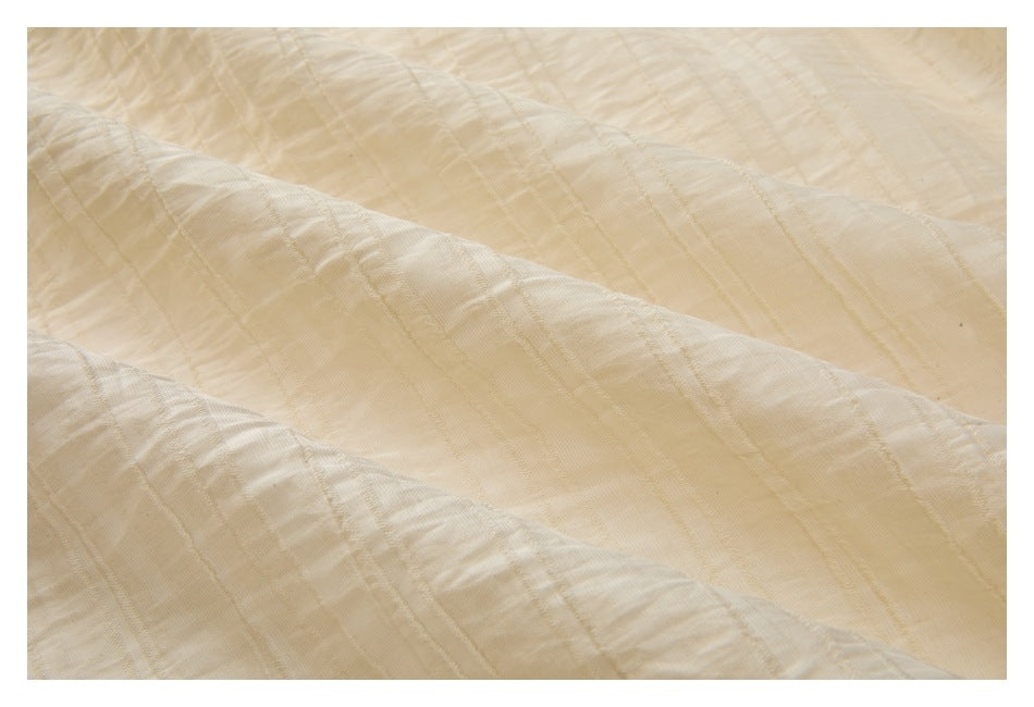Close-up of cream-colored fabric with subtle woven stripes and a softly crinkled texture.