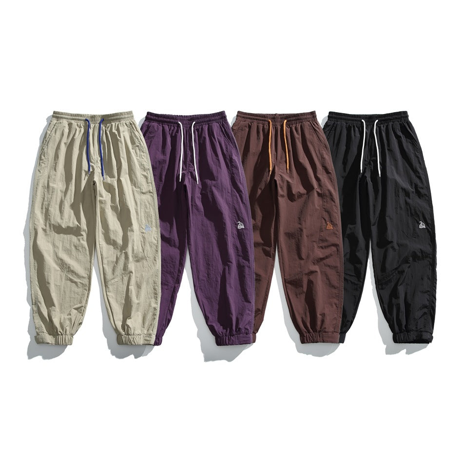 Four pairs of loose jogger pants shown together in light khaki, purple, dark brown, and black.