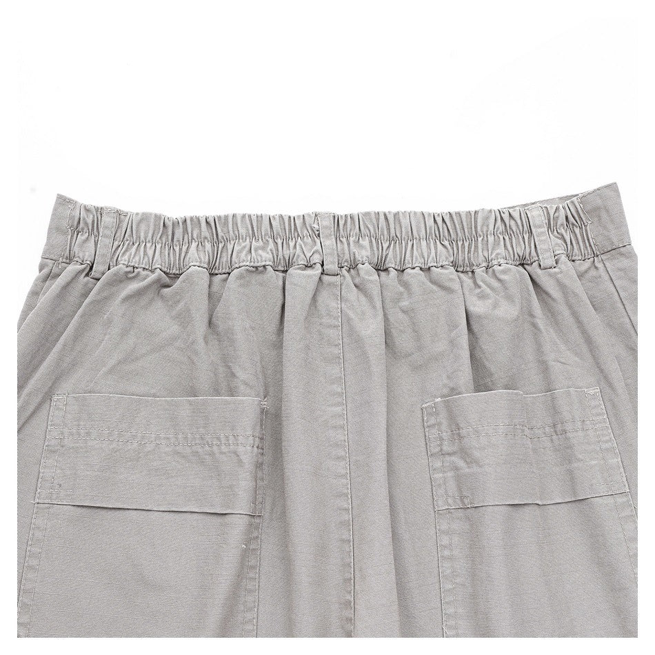 Back view of gray trousers with a gathered elastic waistband and two large patch pockets.
