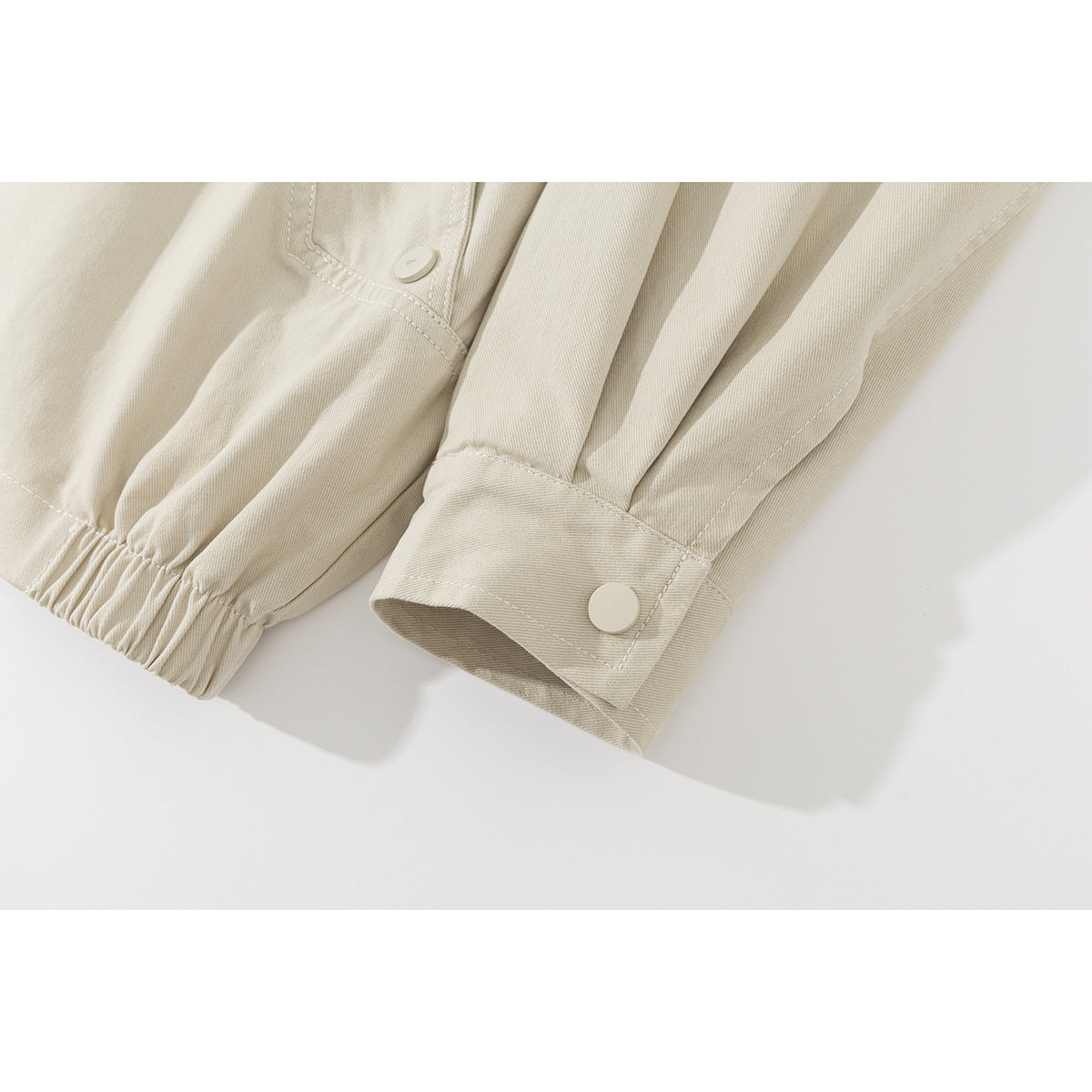 Close-up of the ivory jacket's sleeve cuffs, snap tab, and elasticized hem.