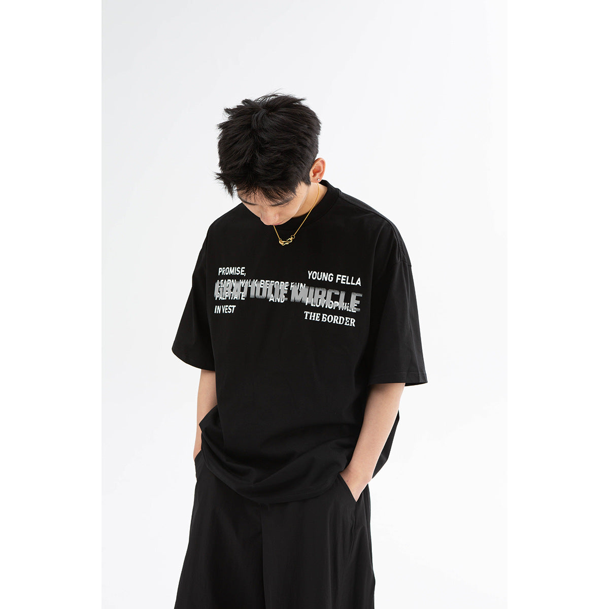 Model wearing an oversized black graphic T-shirt with loose black trousers.