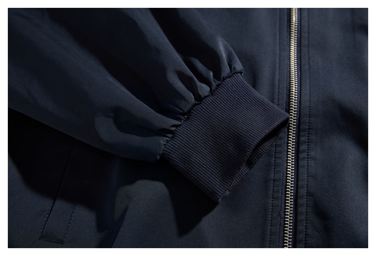 Close-up of a dark navy jacket sleeve with a wide ribbed cuff beside the front zipper.