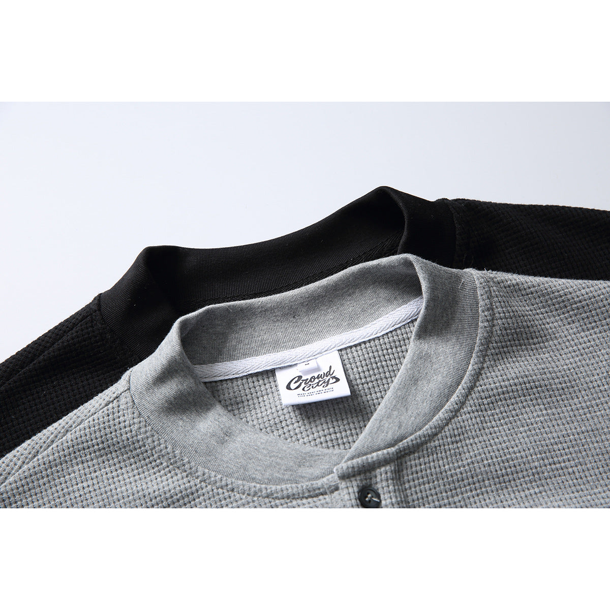 Close-up of a gray textured henley shirt collar and button placket, layered over a black shirt.