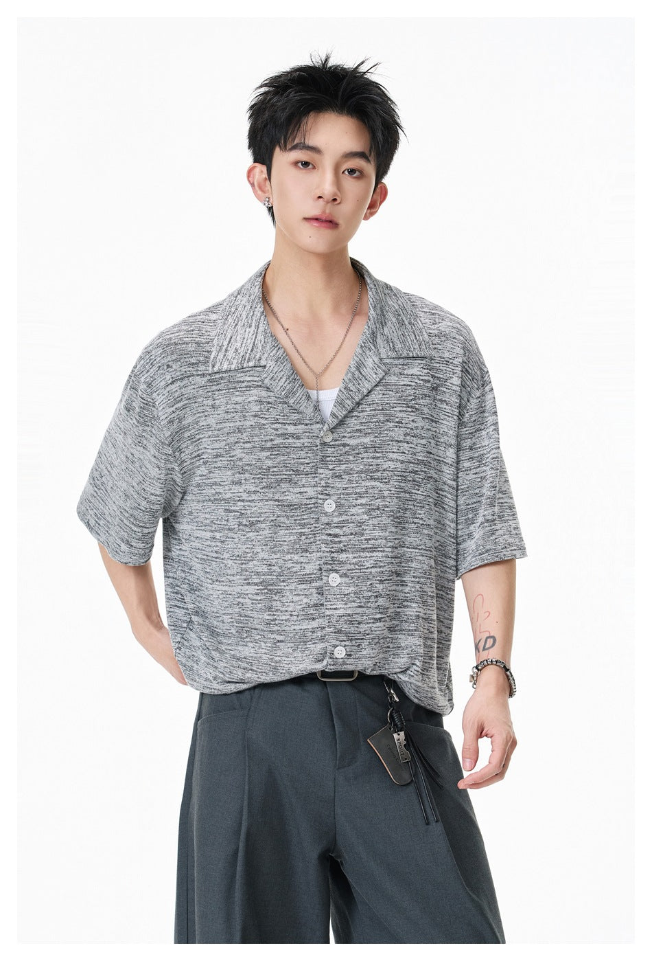 Front view of a model wearing a light gray marled short-sleeve button-up shirt with a wide open collar.