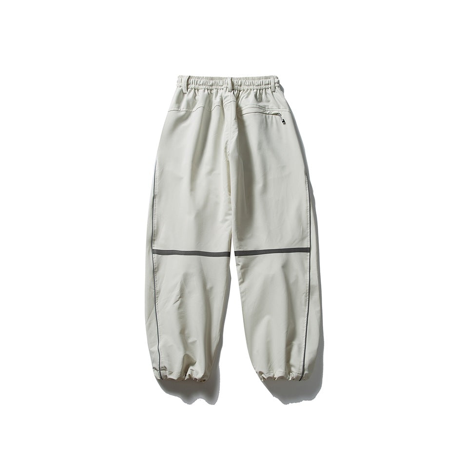 Off-white loose-fit pants shown from the back, with an elastic waist, zip pocket, dark knee bands and gathered cuffs.
