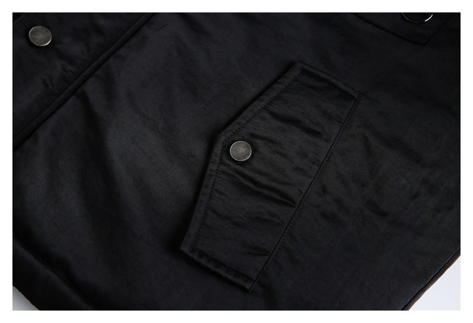 Close-up of a black jacket flap pocket with a round metal snap button.