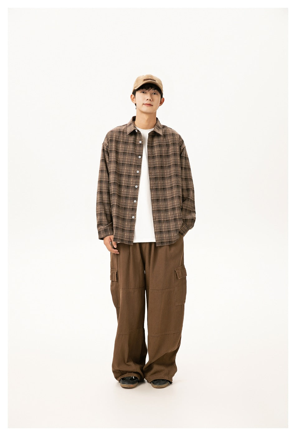 Model wearing brown plaid button-up shirt open over a white tee with brown cargo pants and a tan cap