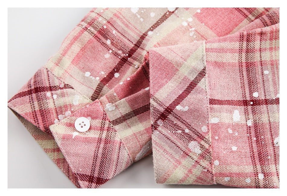 Close-up of a white-buttoned cuff and folded sleeve on a pink plaid shirt with white marks.