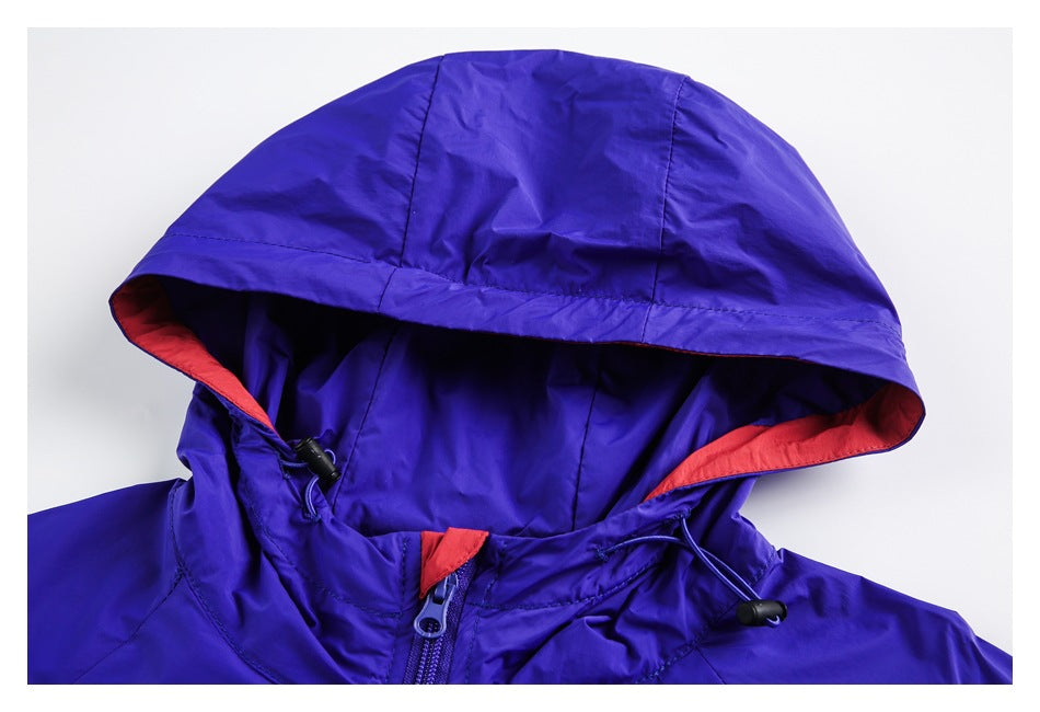 Close-up of a blue jacket hood with red lining, drawcords, and a front zipper.