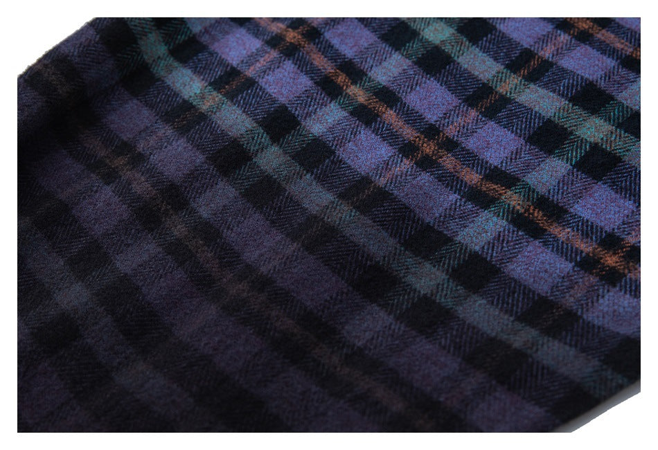 Close-up of dark plaid fabric with purple, teal, and rust lines forming a check pattern.