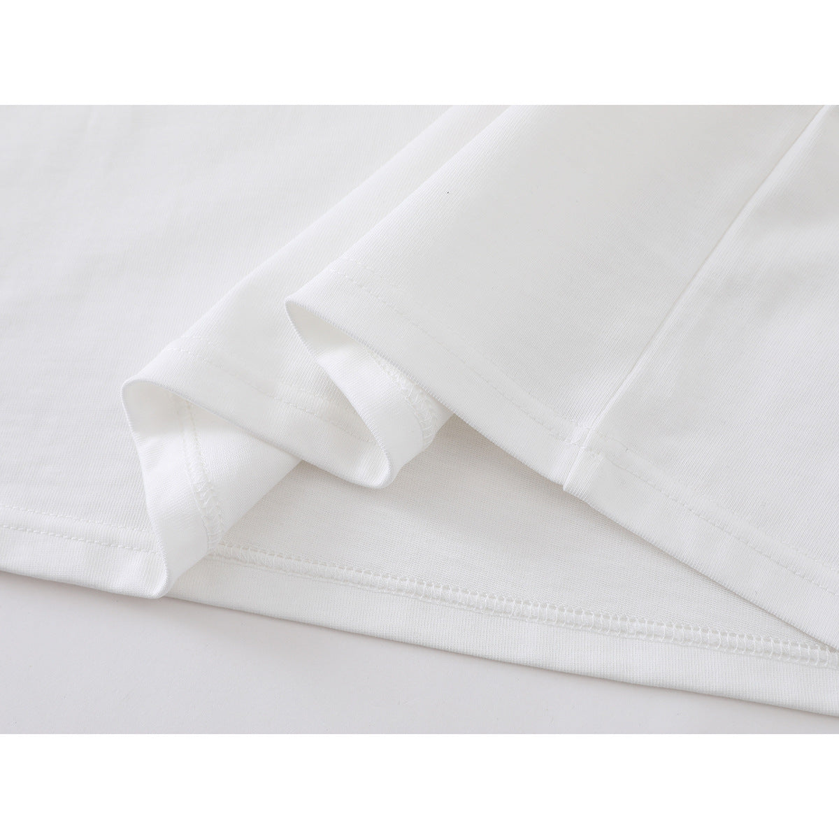 Close-up of the folded white T-shirt hem showing its stitching and seams.