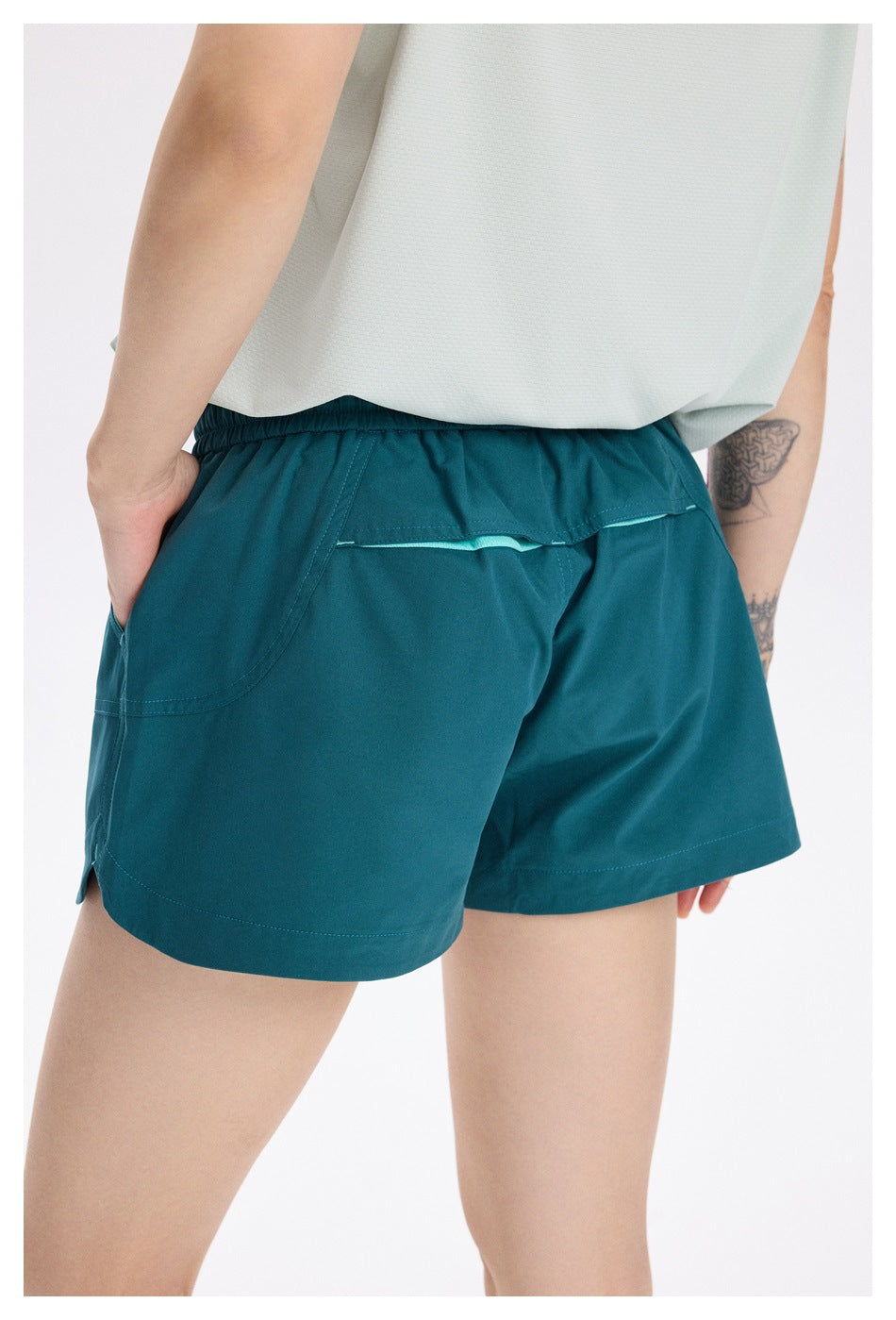 Close-up of the rear of teal running shorts, showing the back pocket, turquoise trim, and curved seams.