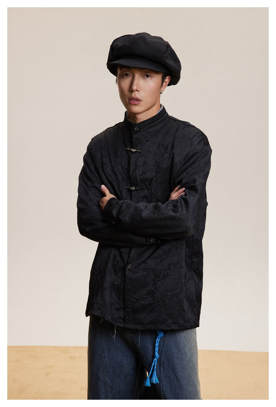 Model wearing a black textured stand-collar jacket with frog closures and subtle tonal embroidery.