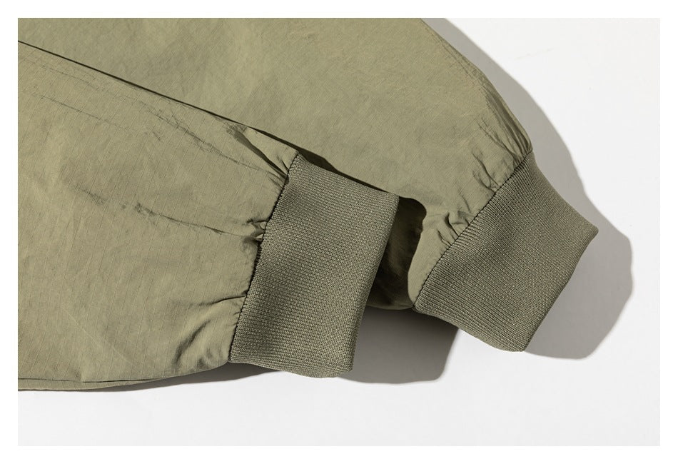 Close-up of an olive-green jacket sleeve ending in a ribbed knit cuff.