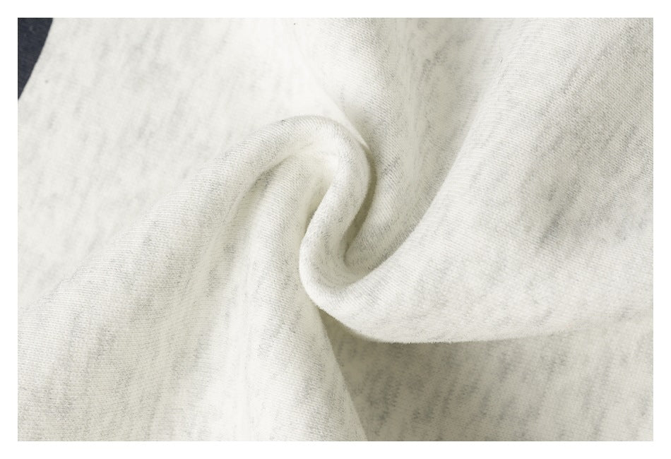 Close-up of off-white heathered sweatshirt fabric folded into a soft swirl.