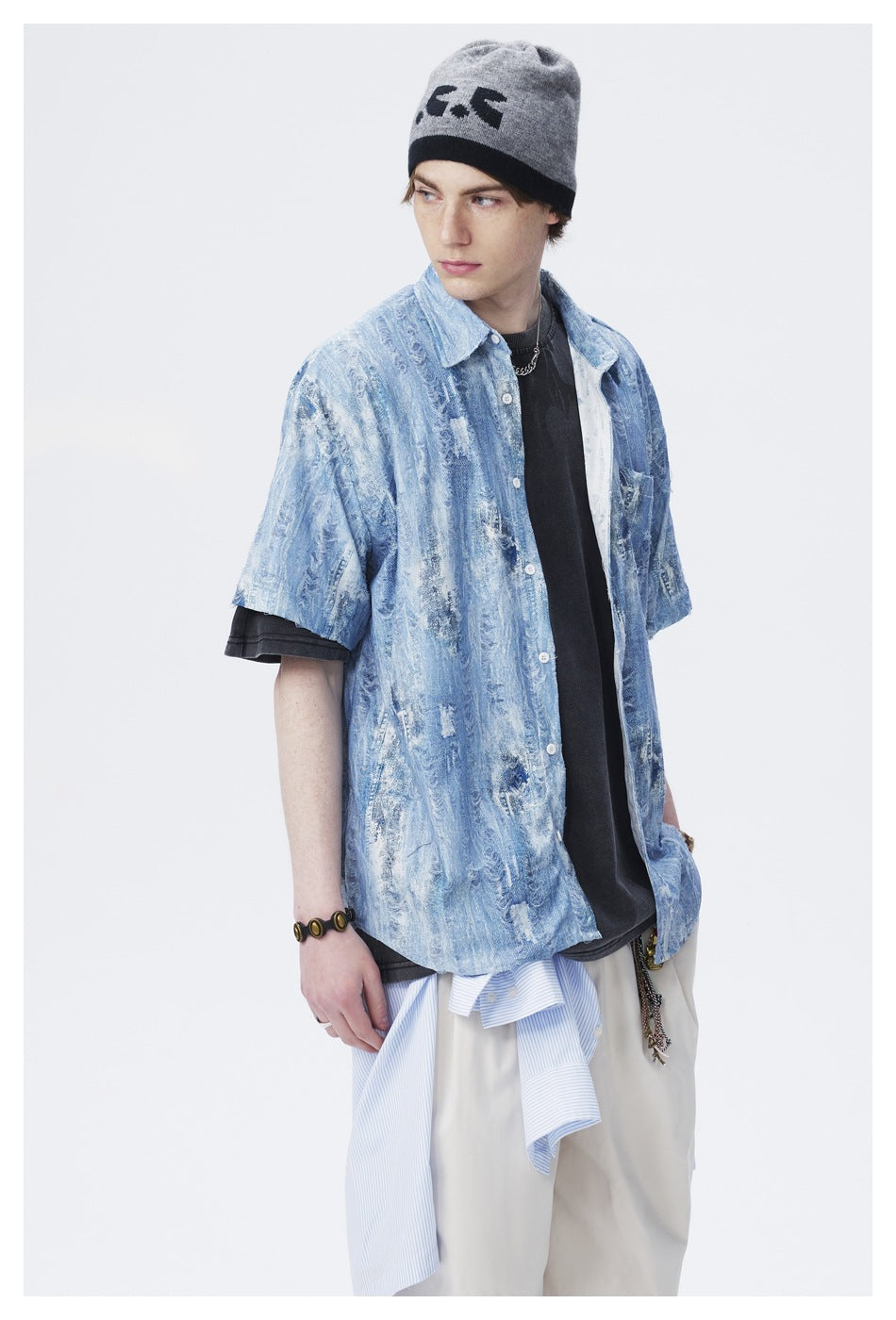 Model wearing a light blue distressed-pattern short-sleeve button-up shirt over a black T-shirt.