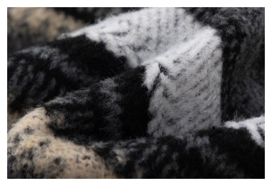Macro view of the fuzzy black, gray, cream, and white plaid fabric texture.