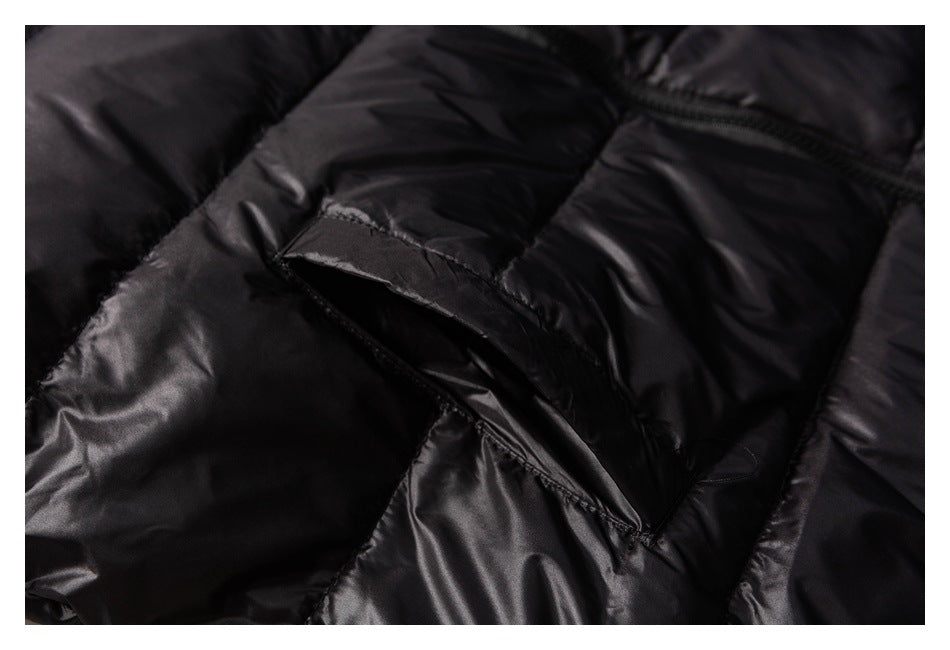 Close-up of a slanted pocket opening on a glossy black quilted jacket.