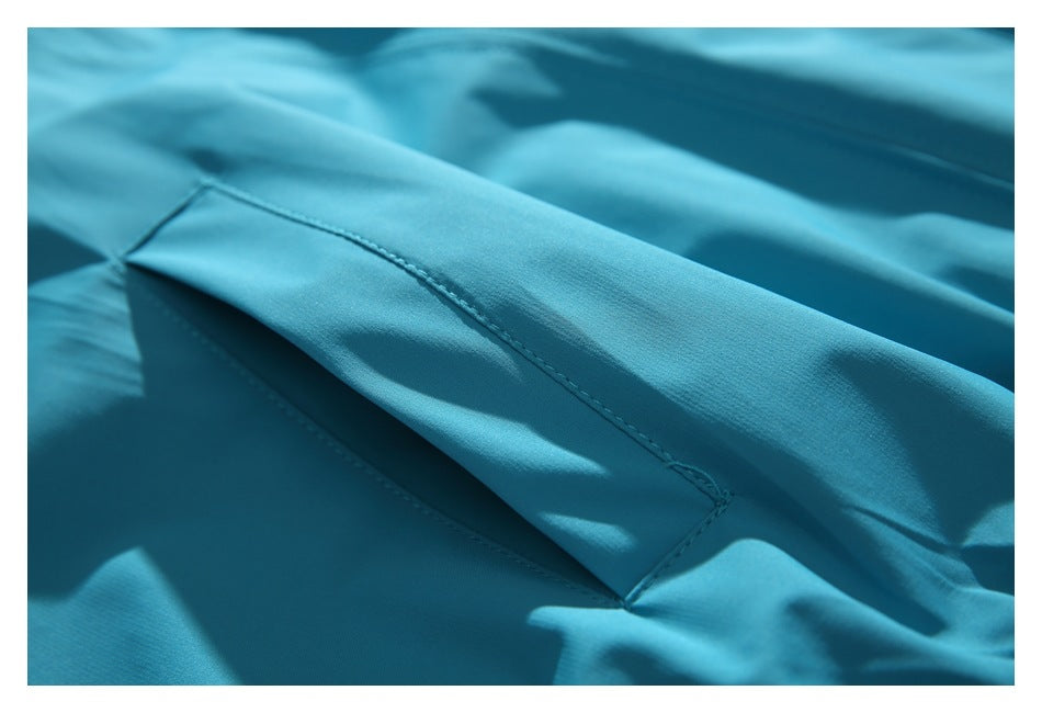 Close-up of a turquoise jacket pocket flap with neat matching stitching.