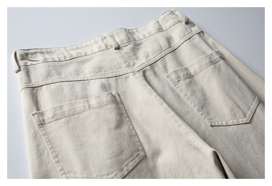 Close-up of light beige trousers showing the rear waistband, belt loops, and two patch pockets.