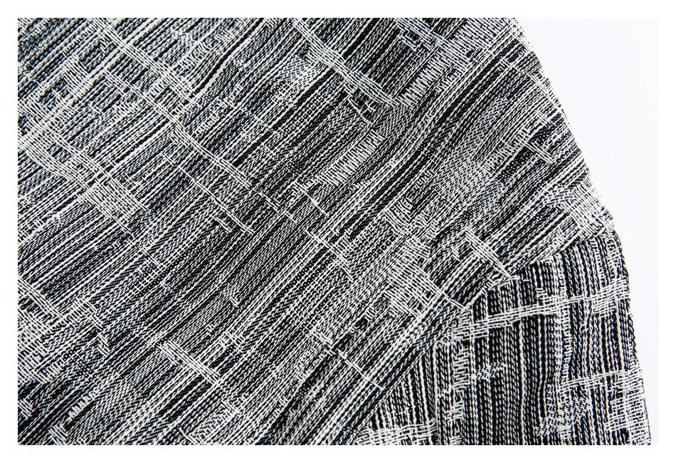 Close-up of a seam and curved edge on black-and-white patterned garment fabric.