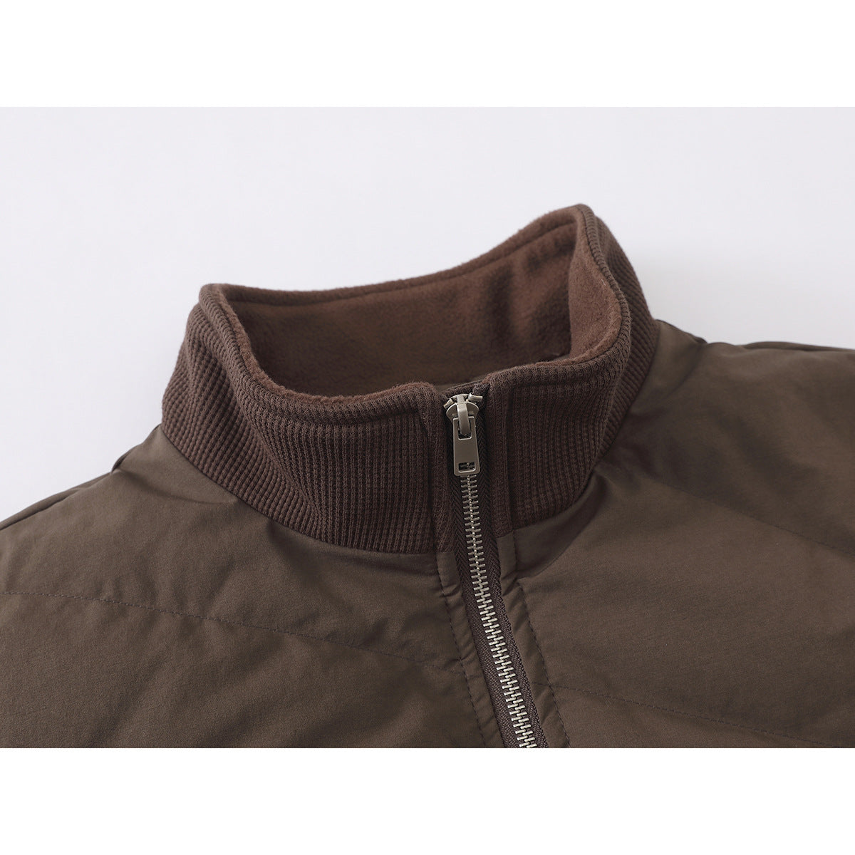 Close-up of a brown jacket’s ribbed stand collar, fleece-like inner lining, and silver front zipper.