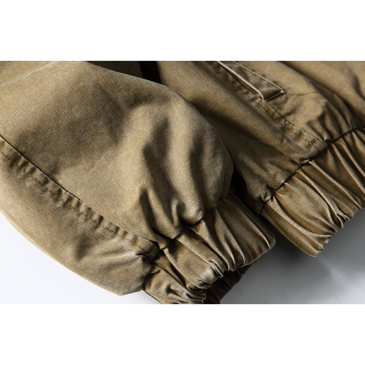 Close-up of the tan-brown jacket's gathered elastic cuffs and sleeve seams.