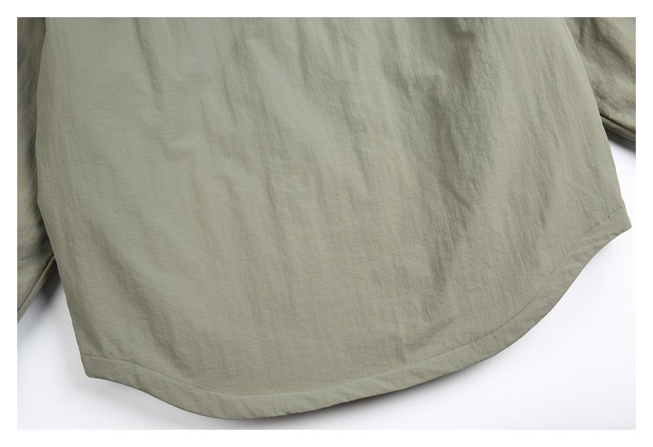 Close-up of the curved bottom hem of a sage-gray shirt.
