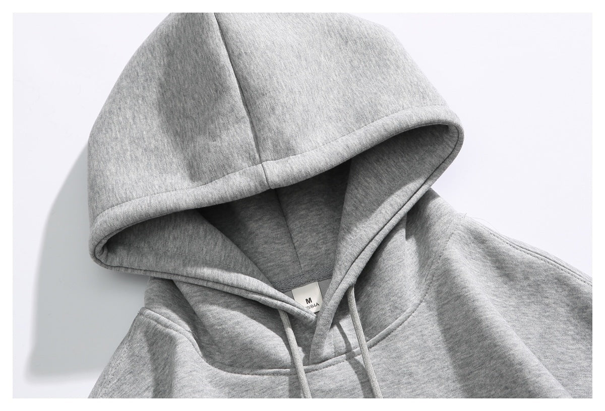 Close-up of a heather gray hoodie’s lined hood, drawstrings, and small neck label.