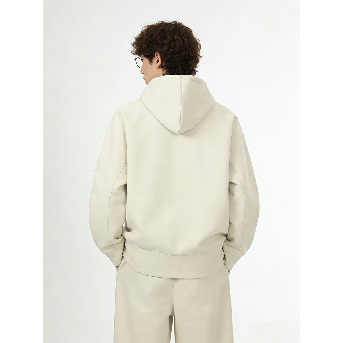Back view of a model wearing an ivory hooded pullover and matching pants.