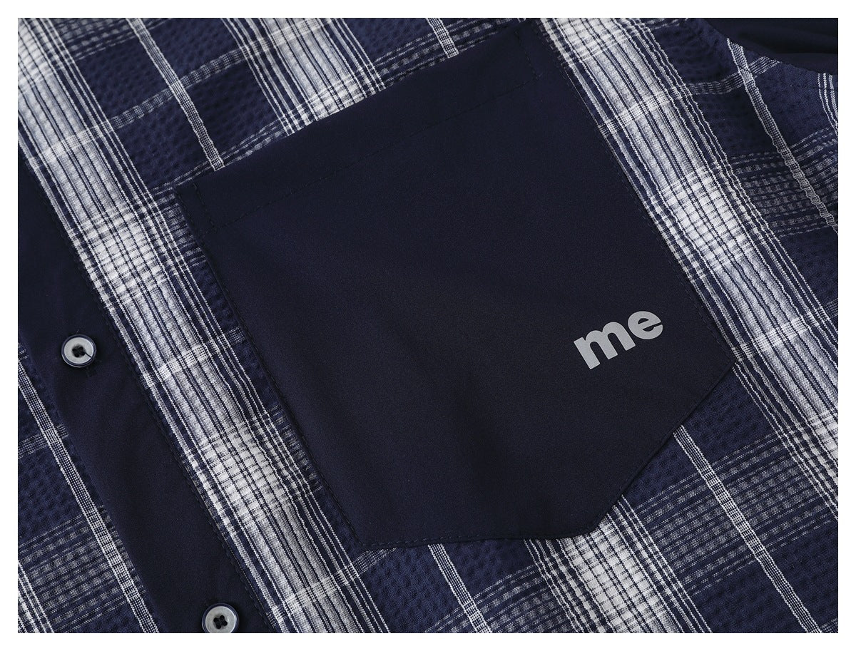 Close-up of a navy pocket with small white “me” lettering on a blue-and-white plaid shirt.