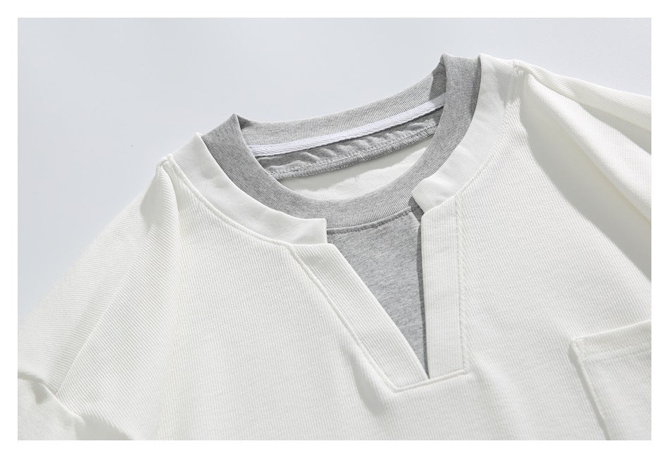 Close-up of a white top with a notched neckline and gray inner collar.
