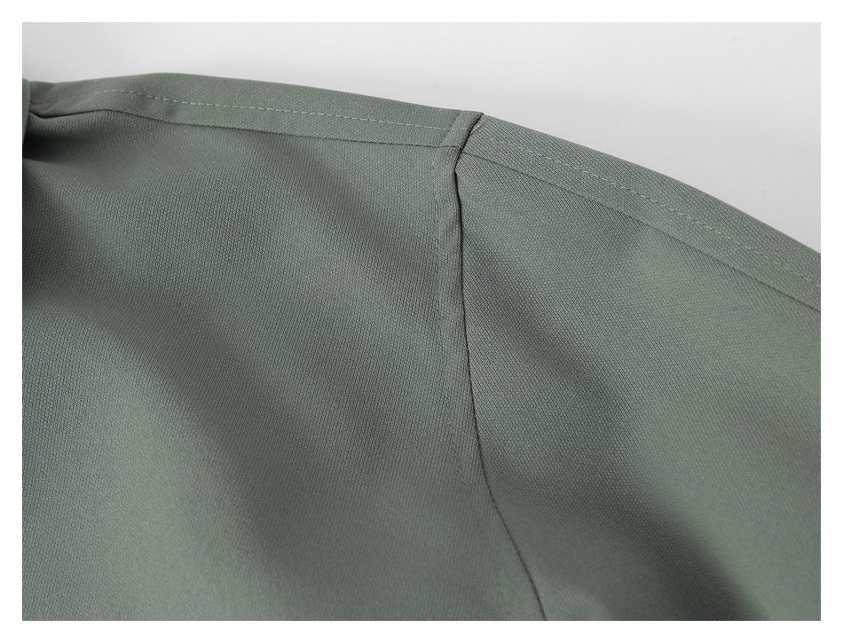 Close-up of the gray-green jacket's shoulder seam and stitching.