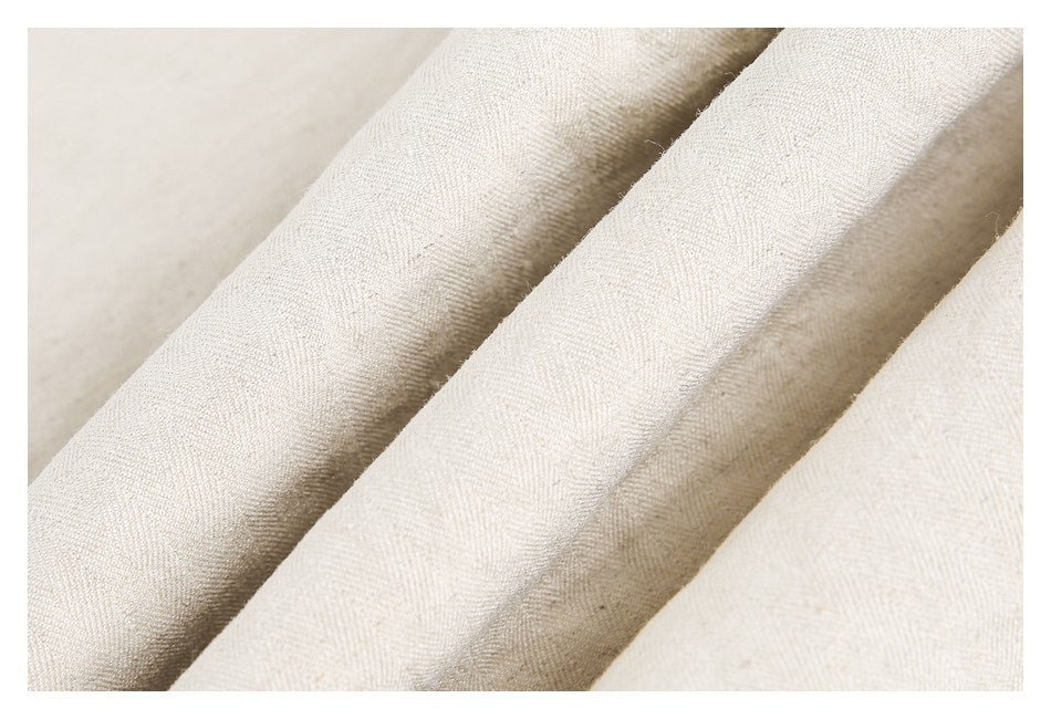 Close-up of off-white woven fabric arranged in soft folds, showing its fine textured surface.