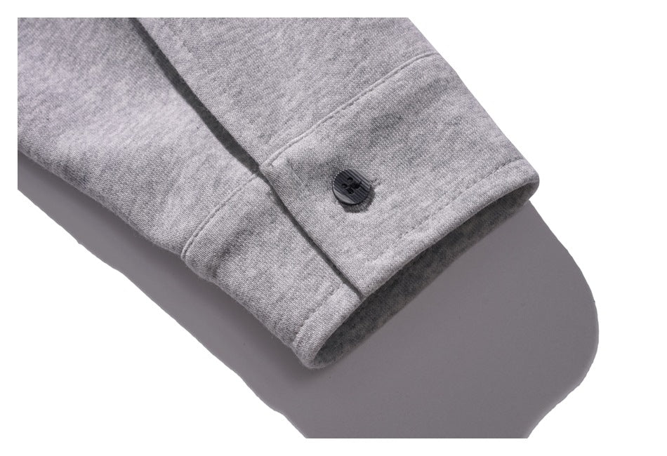 Close-up of a heather gray sleeve cuff with a black button and visible stitching.