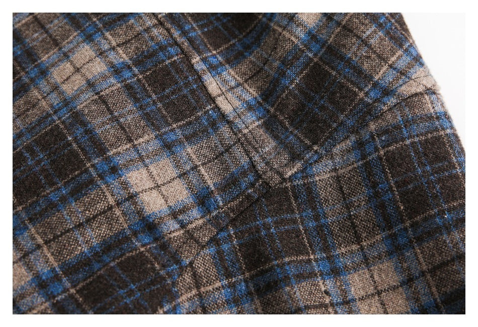 Close-up of a seam across brown, charcoal, and blue plaid fabric.