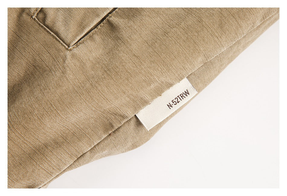 Close-up of a tan garment hem with stitching and a small white sewn-in label reading “N-521RM.”