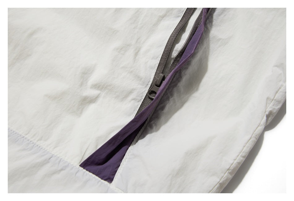 Close-up of a dark zipper opening on the white jacket, showing purple inner fabric.
