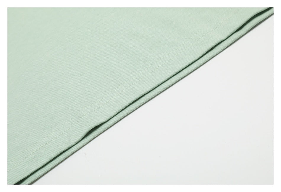 Close-up of pale mint-green fabric with a straight stitched hem against a white background.