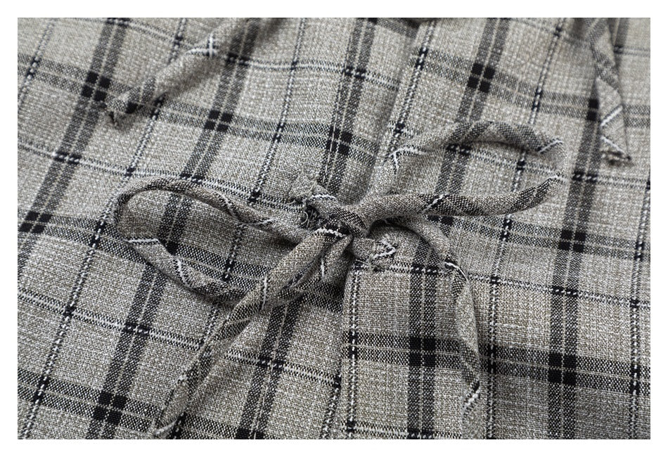 Close-up of the gray plaid blouse's fabric and tied front closure.