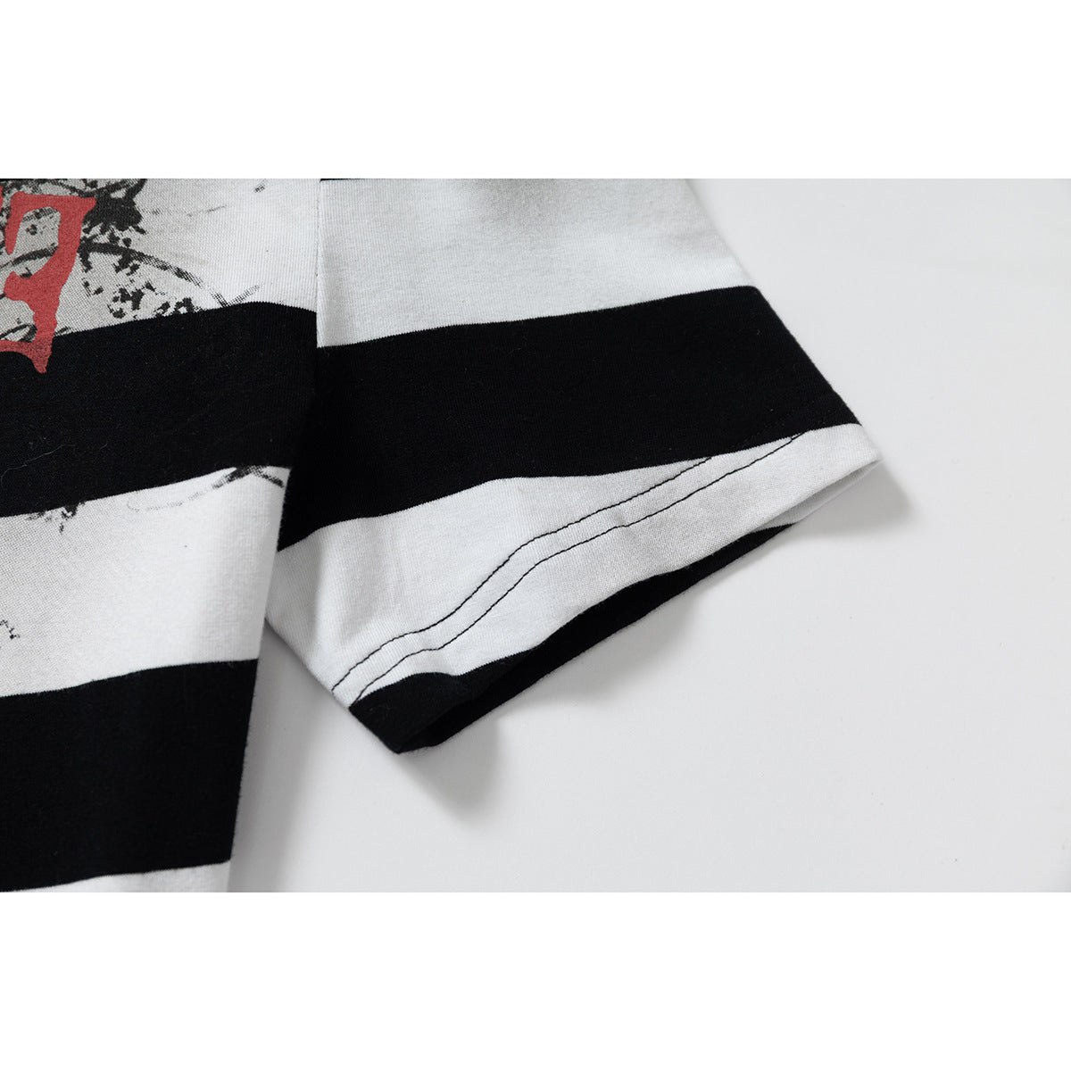 Close-up of a short sleeve and stitched hem on the black-and-white striped shirt.