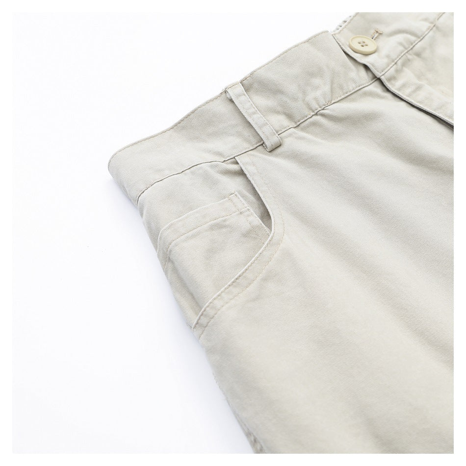 Angled close-up of light beige pants showing a belt loop, buttoned waistband, and curved front pocket.