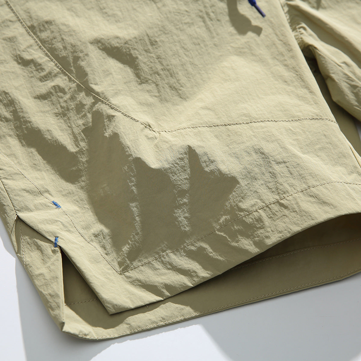 Close-up of beige shorts showing the stitched hem, panel seams, and side vent.