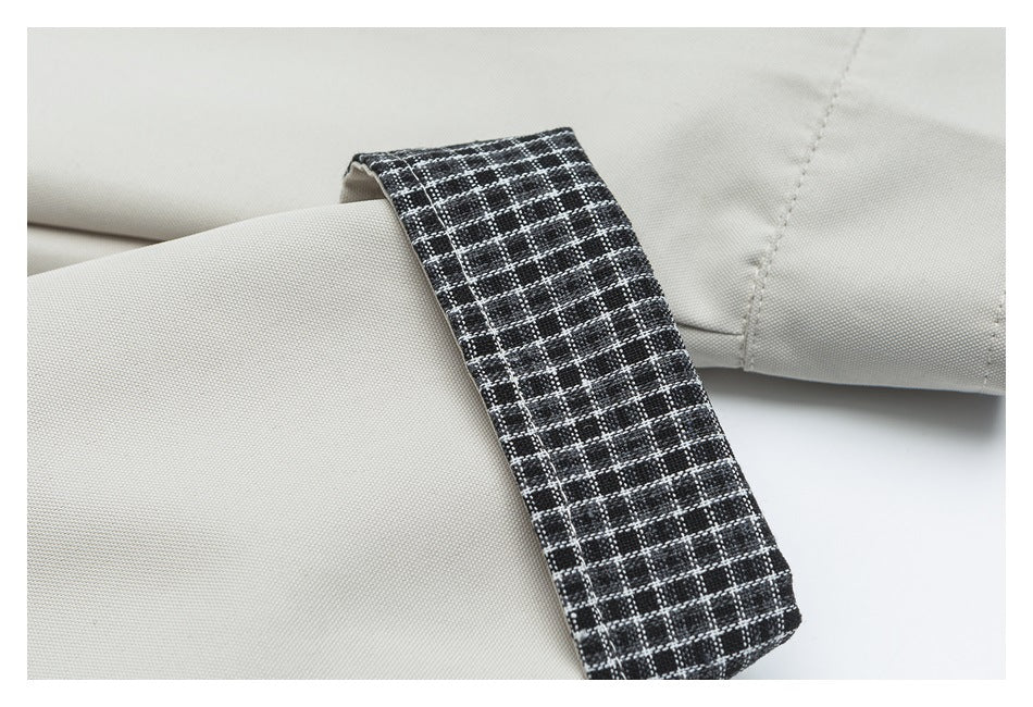 Close-up of a light beige sleeve with a black-and-white plaid cuff tab.