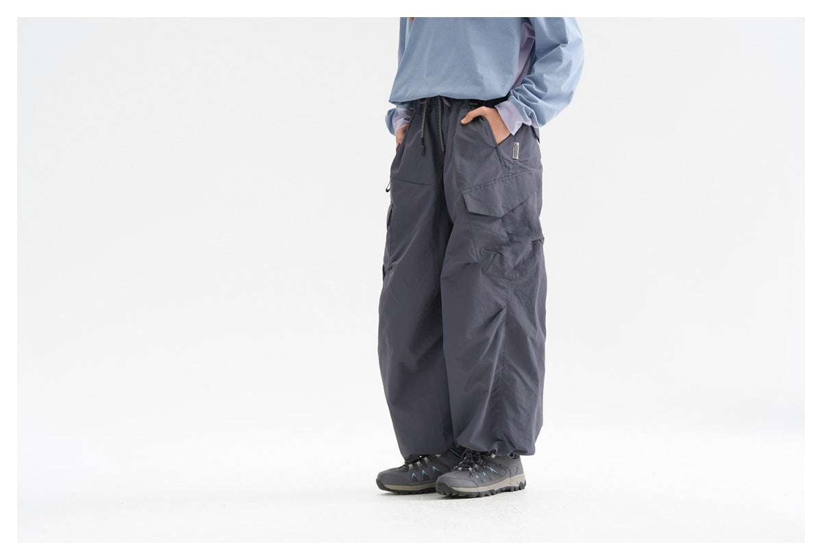 Cropped three-quarter view of a model wearing dark slate wide-leg cargo pants with flap pockets and hiking shoes.