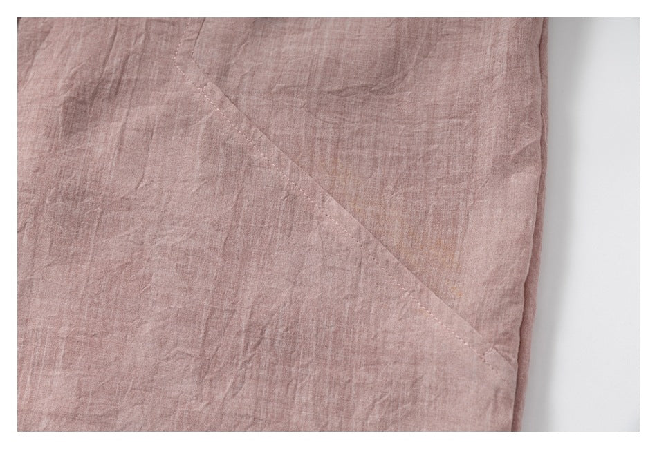 Close-up of dusty rose fabric with a diagonal stitched seam and folded edge.